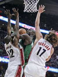 Kevin Garnett, de los Celtics de Boston, en el centro, se eleva para disparar entre Joe Smith y Anderson Varejao de los Cavaliers de Cleveland