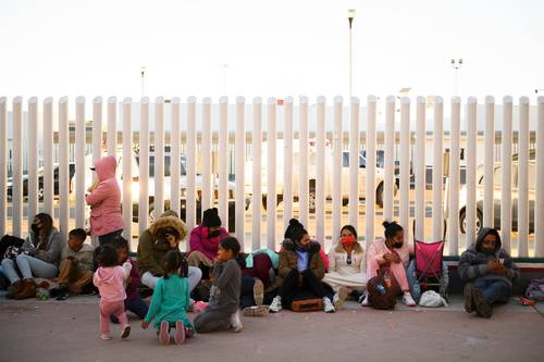 Niños esperan con sus familias en los alrededores de la garita de El Chaparral, en Tijuana, el momento de pasar hacia EU.
