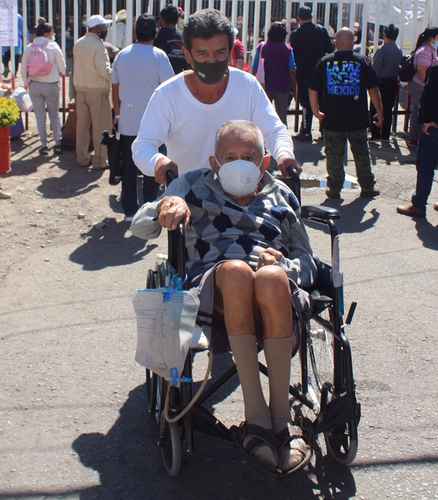 Un hombre de la tercera edad es trasladado por un familiar hacia el módulo de vacunación contra el Covid-19 en el centro de salud de Acatlipa, municipio de Temixco, Morelos, donde se formaron largas filas y prevaleció la desorganización.