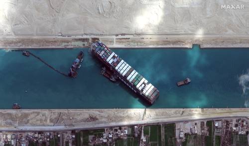 Imagen satelital del carguero Ever Given encallado en el Canal de Suez. Dos remolcadores adicionales se alistan para ayudar en los esfuerzos por liberarlo. Calculan que casi 400 barcos aguardan para utilizar el canal. Además de que muchos otros han sido desviados.