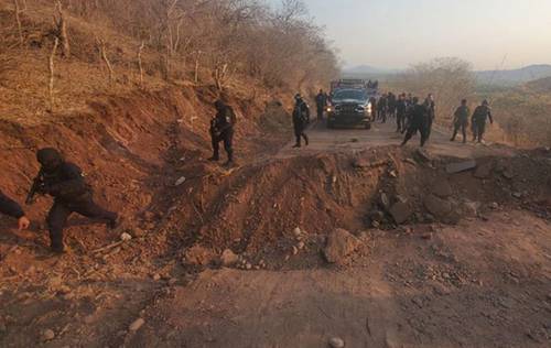 Elementos de la policía de Michoacán vigilan el tramo carretero ubicado entre las localidades de Aguililla y El Aguaje, luego de que presuntos miembros del cártel Jalisco Nueva Generación cortaron la vía.