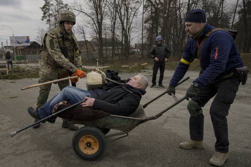  Un ucranio es auxiliado en su empeño de escapar luego de los bombardeos de la aviación rusa en los alrededores de Kiev. Foto Ap