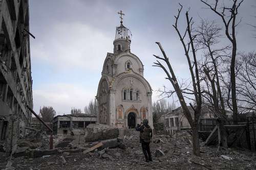 Un militar ucranio toma fotografías de una iglesia dañada después de un bombardeo en un distrito residencial de Mariupol, la ciudad más asediada por ser una localidad portuaria de importancia regional del sureste. Se encuentra situada a orillas del mar de Azov.