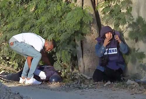  Una colega de Shireen Abu Akleh espera ayuda aterrorizada, mientras un hombre no identificado intenta levantar el cuerpo de la veterana periodista de Al Jazeera, quien fue herida de muerte por disparos en Jenin, Cisjordania reocupada. Foto Afp