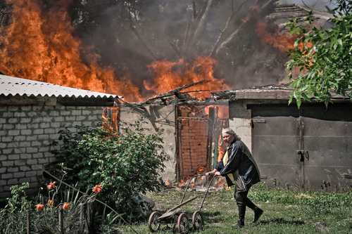 Una mujer se aleja del garaje de una casa en llamas luego deun bombardeo ayer por la noche en la ciudad ucrania de Lysychansk, en la región del Donbás.