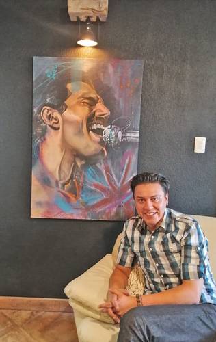 Manuel Padua junto a su cuadro de Freddie Mercury.