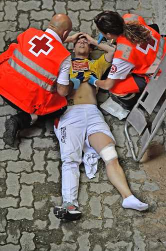  El joven, atendido momentos después por paramédicos durante la pamplonada. Foto Afp