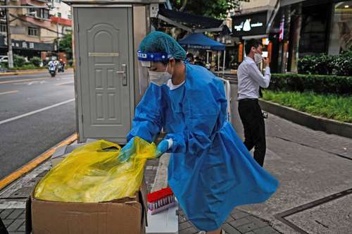 Un trabajador de la salud toma suministros junto a una caseta donde se realizan pruebas para detectar casos de coronavirus en las calles de Shanghái.