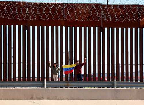 Venezolanos despliegan su bandera antes de entregarse a la Patrulla Fronteriza, en El Paso, Texas, para sumarse a las oleadas de naturales de ese país que solicitan asilo en la ciudad.