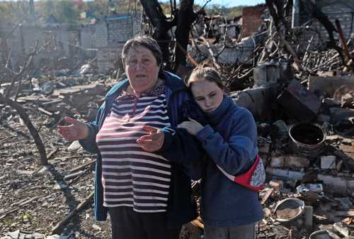 Una menor y su abuela, residentes de la ciudad ucrania de Kupiansk, entre las ruinas de su hogar, luego de un bombardeo.