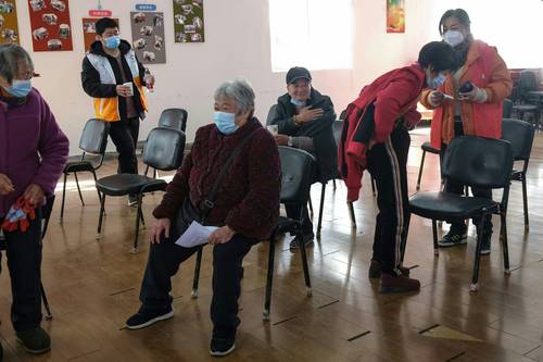 Ancianos esperan recibir vacuna contra covid-19 en Shanghái.