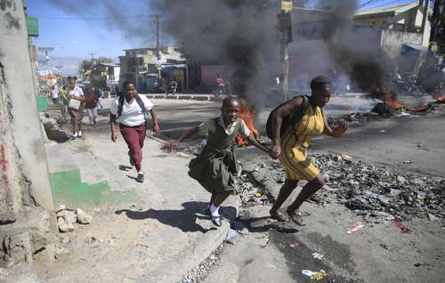 Civiles pasan a toda carrera frente a una barricada levantada por integrantes de la policía que protestan contra la mala gestión de su corporación. Diversas calles de Puerto Príncipe fueron bloqueadas un día después de que las pandillas, que tienen el control de buena parte de Haití y que se financian con recursos que obtienen de secuestros, atacaron la sede de la policía en Liancourt, un poblado al norte de la nación, y mataron a seis policías. Los manifestantes intentaron asaltar la oficina del primer ministro, Ariel Henry, y entraron en la pista del aeropuerto internacional Toussaint Louverture hasta interrumpir el tráfico aéreo.