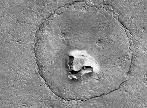 Científicos explican la impresión de un “oso” en la superficie de Marte. Apareció como si hubiera sido tallado ante la cámara del Orbitador de Reconocimiento del planeta. Los expertos a cargo de HiRISE procesaron las imágenes y publicaron el retrato. “Hay una colina con una estructura que colapsó en forma de V (el hocico), dos cráteres (los ojos) y una fractura en forma de círculo (la cabeza)”, reseñaron los especialistas en la Universidad de Arizona, responsables del sistema. “La pauta de fractura circular se podría al asentamiento de un depósito sobre un cráter de impacto enterrado”, precisaron.