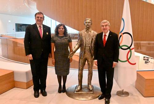 El canciller Marcelo Ebrard, María José Alcalá, titular del COM, y Thomas Bach, presidente del COI, flanquean una estatua del barón Pierre de Coubertin, creador del movimiento olímpico.