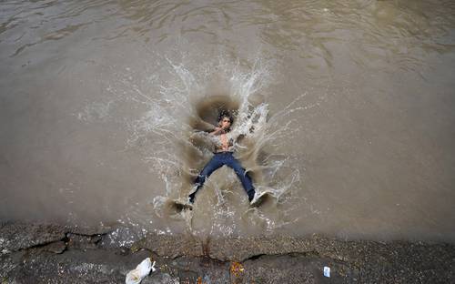 Un niño salta a un canal en Jammu, India. Varias regiones de ese país enfrentan un calor abrasador en este verano.