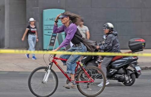 Sobre Paseo de la Reforma un ciclista sostiene su visera para evitar que se la vuele el viento.