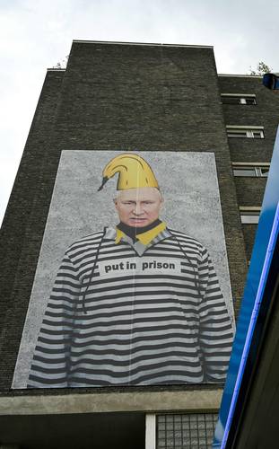 Una gran pancarta colocada en la fachada de un edificio en Colonia, Alemania, muestra una imagen del artista alemán Thomas Baumgaertel del presidente ruso Vladimir Putin vestido de presidiario. “Métanlo a la cárcel”, se lee en su pecho.