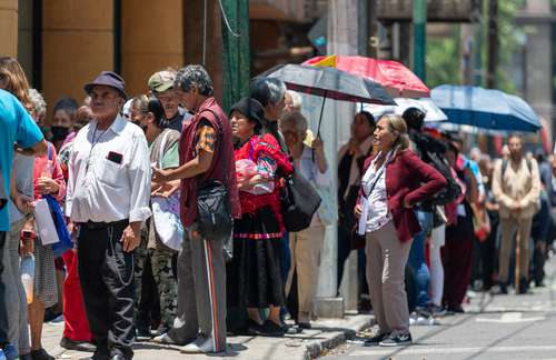 Adultos mayores afuera de una sucursal del Banco del Bienestar en espera de cobrar apoyos sociales.