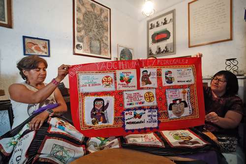 Claudia Vélez y otra integrante de Yaocihuatl muestran uno de los bordados que han realizado.