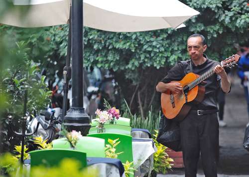 Un músico urbano ameniza la estadía de comensales durante la hora del almuerzo en un restaurante del centro de Coyoacán.