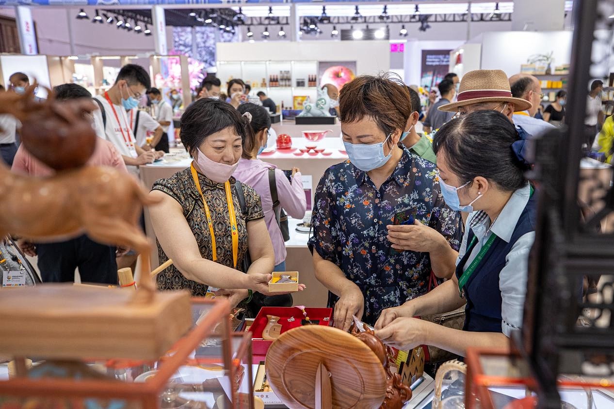 En la primera Feria Internacional de Bienes de Consumo de China, el personal de los expositores presenta productos de marca al público
