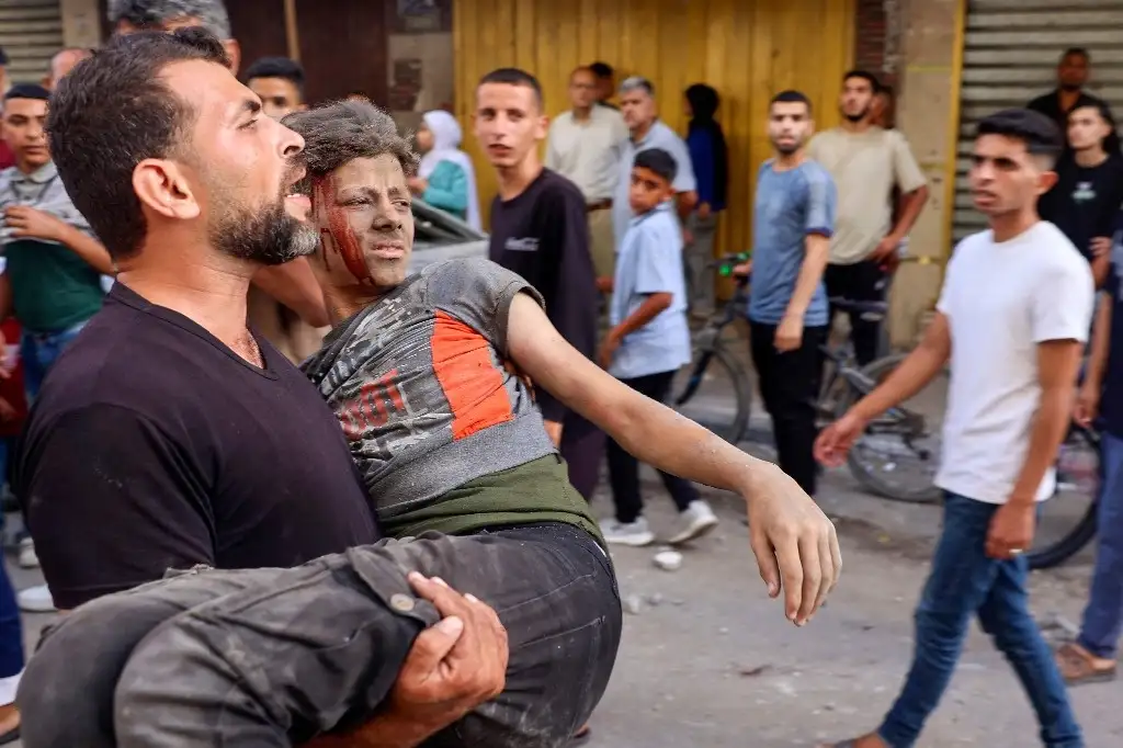 Un joven palestino herido es trasladado para ser atendido, ayer, tras un bombardeo israelí en Al Bureij, en Gaza. Foto Afp
